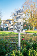 Wooden direction indicator with famous Italian place names in a garden