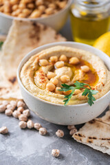 Hummus, chickpea dip, olive oil, raw beans, smoked paprika, pita on grey authentic background. Middle eastern, jewish cuisine or arabic dishes. Macro view. Copy space. Vegan, vegetarian food concept