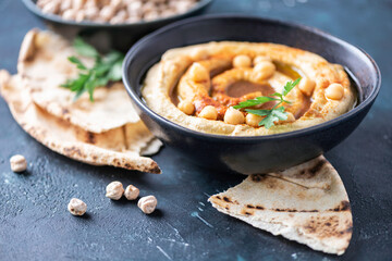 Chickpeas hummus, olive oil, raw chickpeas, smoked paprika, pita on dark background. Middle eastern, jewish cuisine or arabic dishes. Top view. Copy space. Snacks set. Vegan, vegetarian food concept