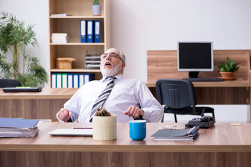 Old male employee suffering from radiculitis at workplace