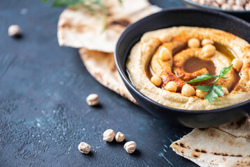 Chickpeas hummus, olive oil, raw chickpeas, smoked paprika, pita on dark background. Middle eastern, jewish cuisine or arabic dishes. Top view. Copy space. Snacks set. Vegan, vegetarian food concept
