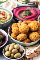 Arabic traditional cuisine. Middle Eastern meze with pita, olives, colorful hummus, falafel, stuffed dolma, babaganush, pickles, vegetables, pomegranate, eggplants. Mediterranean appetizer party idea