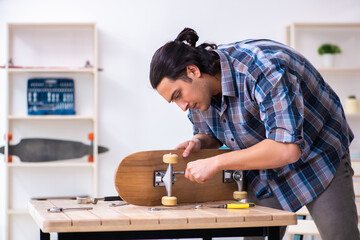 Young man repairing skateboard at workshop