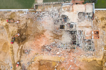 Aerial view of construction site with destroyed industrial building and excavators.