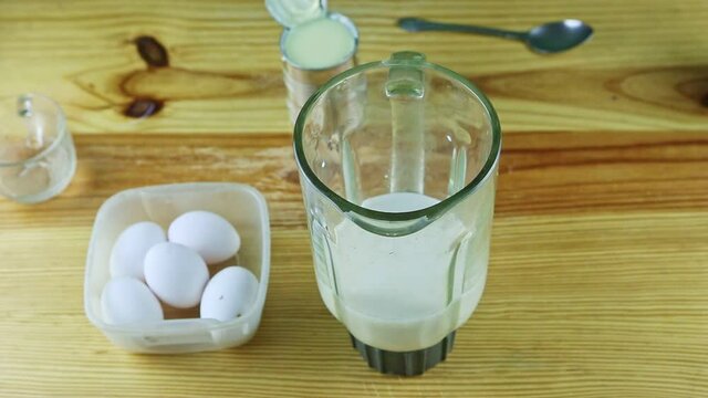 slowly zoom out from glass blander chalice with milk, white eggs, and steel cans