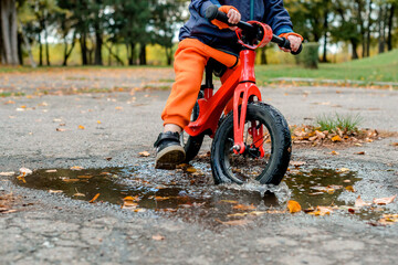 child riding a bike into a puddle