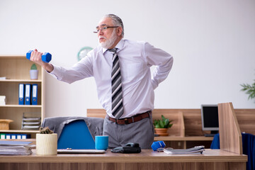 Old male employee suffering from radiculitis at workplace