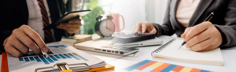 Fototapeta premium Businesswomen hands working with finances about cost and calculator and laptop with tablet, smartphone at office in morning light
