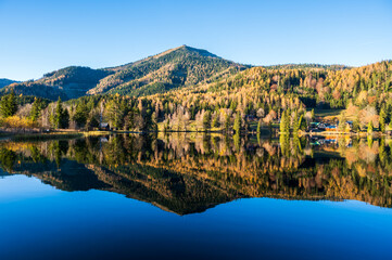 A hill reflected in the clear waters of lake Erlaufsee on a sunny autumn day