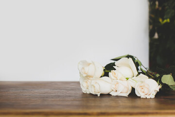 Composition with white roses on white and wooden background