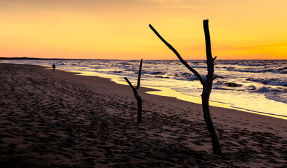 Sunset by the sea. Sandy waves and small quiet waves. Calm sea.