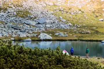 Man and woman are standing near the tent. Lake and camping in the Carpathian mountains.
