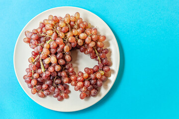 a bunch of ripe juicy grapes on a plate on blue surface