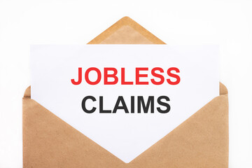 A white sheet with the text jobless claims lies in an open craft envelope on a white background with copy space. Business concept image