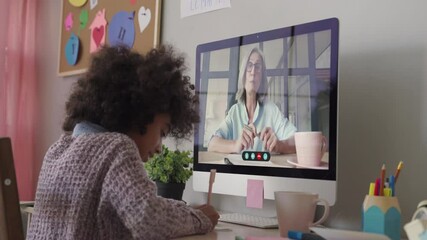 Smart small african school child girl online learning with online remote teacher or web tutor studying at home on computer taking notes. Tutoring, homeschool social distance virtual education concept. - Powered by Adobe