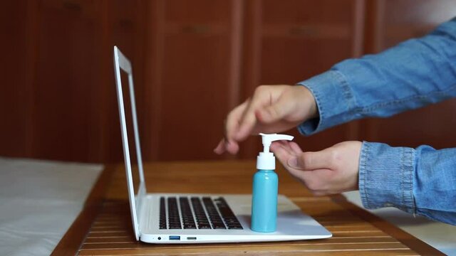 Office worker disinfecting hands at work. COVID-19.