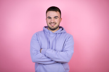 Young handsome man wearing casual sweatshirt over isolated pink background with a happy face standing and smiling with a confident smile showing teeth with arms crossed