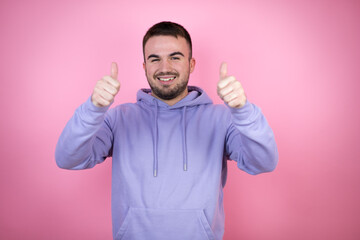 Fototapeta premium Young handsome man wearing casual sweatshirt over isolated pink background smiling and doing the ok signal with her thumbs