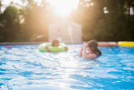 Blurred image of two children swimming in a pool with a light flare 2