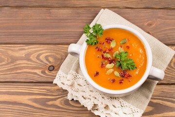 Pumpkin cream soup with herbs and spices, on a wooden background. View from above