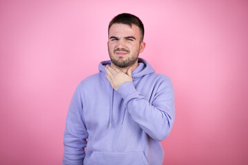 Young handsome man wearing casual sweatshirt over isolated pink background touching painful neck, sore throat for flu, clod and infection
