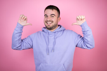 Fototapeta premium Young handsome man wearing casual sweatshirt over isolated pink background looking confident with smile on face, pointing oneself with fingers proud and happy.