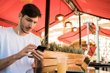 Young man using mobile phone at coffee shop.