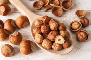Hazelnut kernels in a large wood spoon over white wood table. Healthy vegetarian eating, antioxidant and protein source. Ketogenic and raw food diets ingredient.