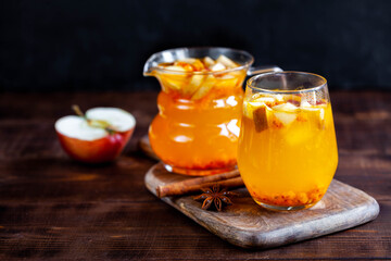 Hot winter drink with buckthorn^ apple and cinnamon on dark wooden table, close-up