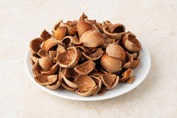 Close-up of hazelnut shells on a small white plate. Healthy vegetarian eating, antioxidant and protein source. Food waste and peelings.