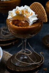 Pumpkin mousse and whipped cream served in tall glasses against black background