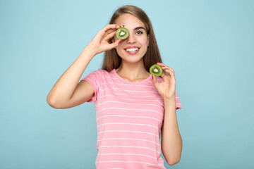 Young girl holding kiwi fruit on blue background