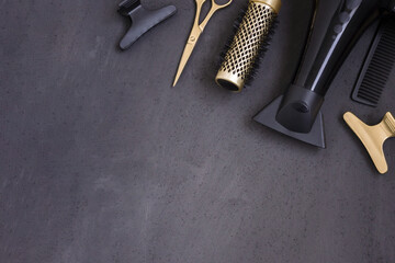 Hairdressing tools in black and gold on a gray concrete background. Hair salon accessories, hair...