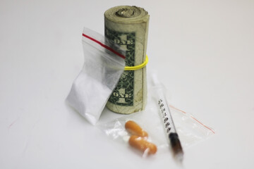 Frontal close-up view of a roll of banknotes with drugs from the cocaine trade, all placed on a...