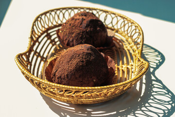 Two delicious handmade chocolates truffle in wickers plate on white background.