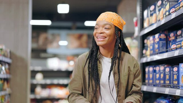 Young confident attractive african woman hearing favorite music track in supermarket dancing and swinging having fun. Entertainment. Joyful people. Shopping concept.