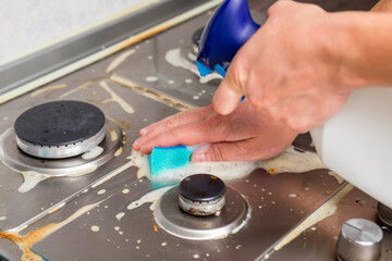 Man hand cleaning gas stove using sponge and detergents. Cleaning a gas stove with kitchen...