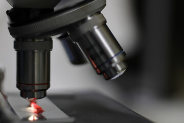 close-up side view of a biological microscope, while analyzing a red wool thread.