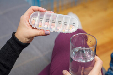 Woman taking medication. Woman holding a pills box and a glass of water. Healthcare concept with medicines