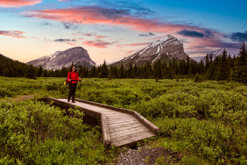 Fototapeta na wymiar Female Backpacker Hiking in Canadian Rockies. Colorful Twilight Sky Art Render. Taken near Banff, boarder of British Columbia and Alberta, Canada. Concept: Explore, Adventure, Trekking, Backpacking