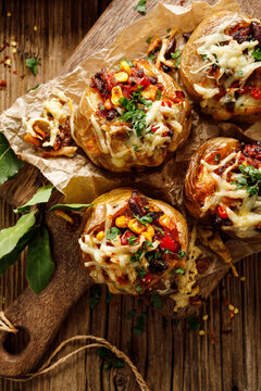 Mexican style baked potatoes with Chili con carne filling and  cheese  served on a cutting board top view