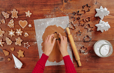 making Christmas gingerbread in the different form on a brown wooden background. cutting man shapes...
