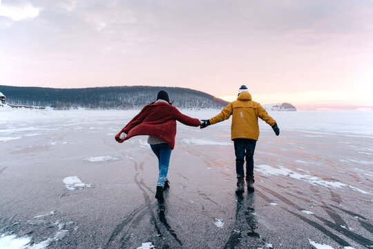 Winter lake and a couple of young couple having fun - ice sliding without skates
