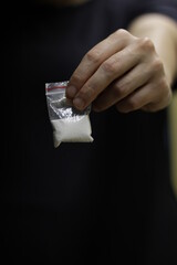 A girl who peddles, while holding out her arm, holding a transparent sachet with powdered cocaine inside, to snort.