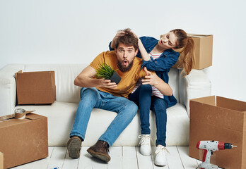 cheerful man and woman on the couch moving interior cardboard boxes