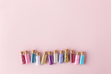 Sparkling confetti or powder in glass bottles in row with copy space for text. Simple minimalist greeting card for holidays, new year, birthday or xmas. Glitter and dust in tubes, background