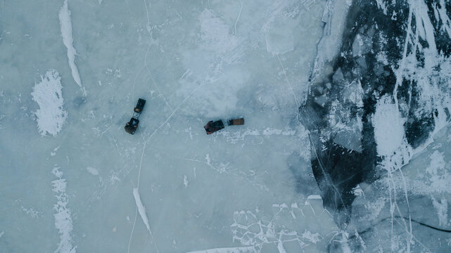 drone view of two old-school snowmobiles driving through the icy river