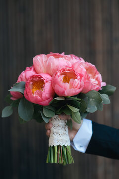 Groom's hand with a bouquet made of peonies