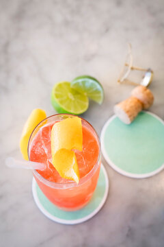 Overhead view of pink drink on coaster on marble table with cut limes.