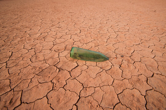 aged glass bottle stuck in the mud as a symbol of drought